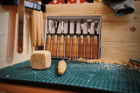 Carving tools and small wooden objects on a workbench