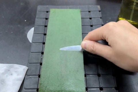 Carving knife bevel resting on a green leather strop