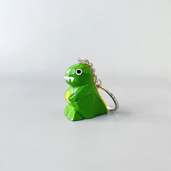 Side view of a dinosaur keychain with hand-painted details, including white teeth and big eyes, showing its cartoonish design.