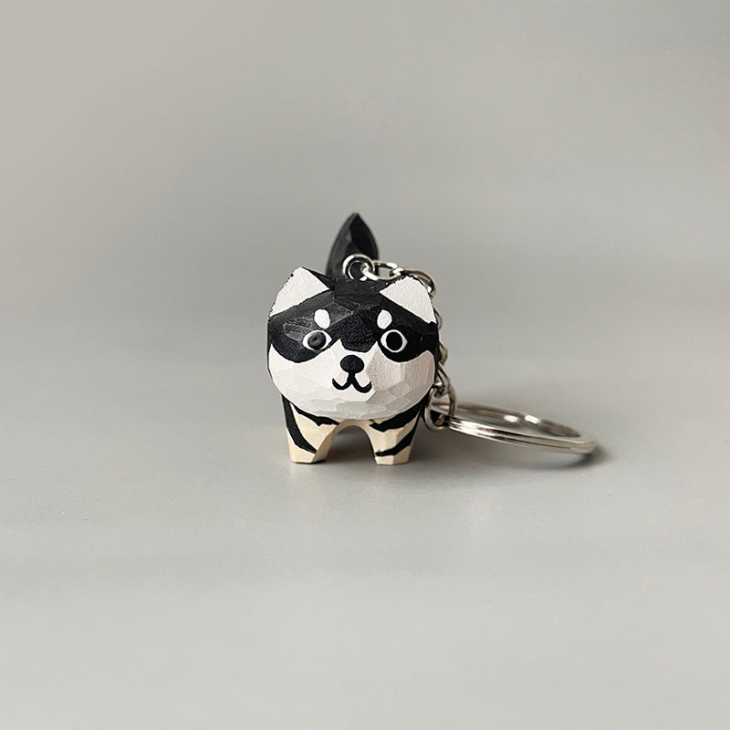 Single hand-carved dog keychain with a close-up of its front, highlighting its black and white paint and big eyes