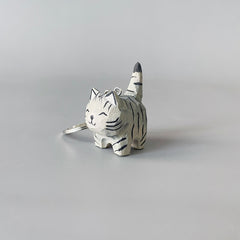 Side view of hand-carved black stripe gray cat keychain with a smiling face.
