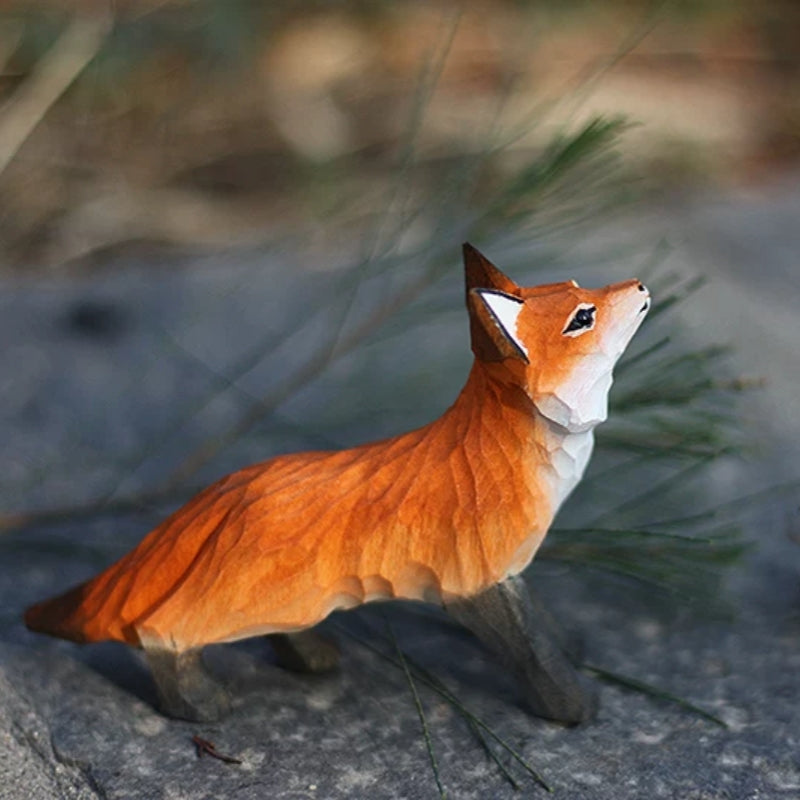 Crouching red fox figurine outdoors with grass