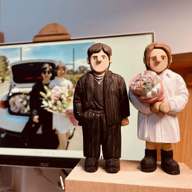 Hand-carved custom figurine of a couple holding flowers with a car in the background.