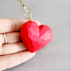 Close-up of a hand holding a red heart keychain