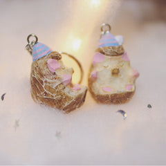 Side view of two hedgehog keychains with pastel-painted details and tiny party hats, showcasing their intricate carving and design.