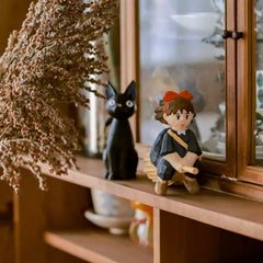 Kiki and black cat wooden figurines on cabinet shelf