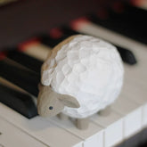 Lamb wooden figurine resting on piano keys