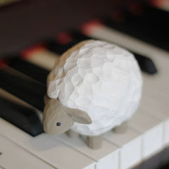 Lamb wooden figurine resting on piano keys