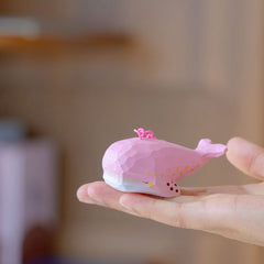 Hand-carved pink whale keychain resting on a person's palm, showcasing its detailed craftsmanship.