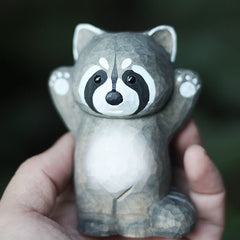 Raccoon wooden figurine held in hand for scale