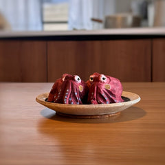 Two red octopus wood sculptures facing each other