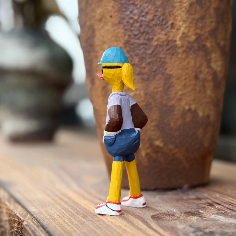 Side view of the wooden Duck figure with a cap, shorts, and red-and-white sneakers