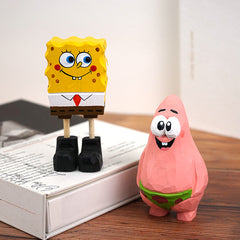 Detailed hand-crafted wooden figures of Spongebob and Patrick on a book.