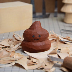 Smiling wooden toy poop, expertly carved and hand-painted, placed on a crafting workspace.