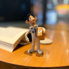 Wooden astronaut figurine holding parcel angled view