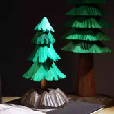 Hand-carved wooden Christmas tree decoration with tiered green branches and a detailed brown base, perfect for tabletop holiday décor.
