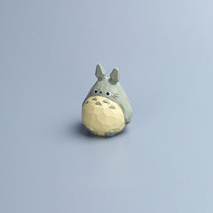 Hand-carved wooden Totoro figurine with painted details, standing alone on a light blue background.