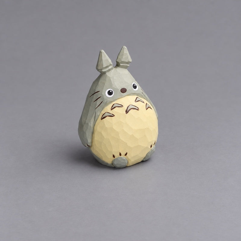 Angled front view of the large wooden Totoro figurine with its rounded belly, low-hanging arms, and two feet.