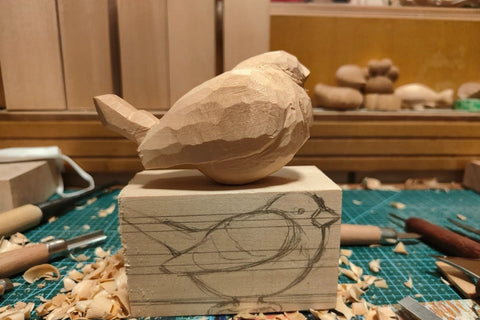 Rounded wooden bird above a block with a side-profile drawing