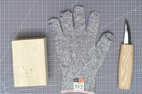 Cut-resistant glove, carving knife, and wood block on a cutting mat