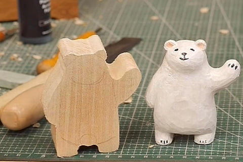 Rough wooden bear blank beside a painted white bear with one raised arm.