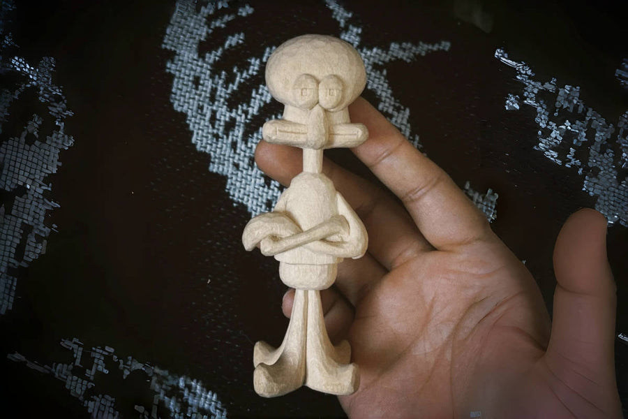 Unpainted Squidward carving showing the projecting face, crossed arms, and feet