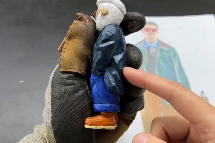 Painted wooden gifts figurine showing detailed clothing folds and coat-to-arm transitions in wood carving.