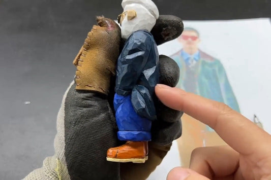 Painted wooden gifts figurine showing detailed clothing folds and coat-to-arm transitions in wood carving.