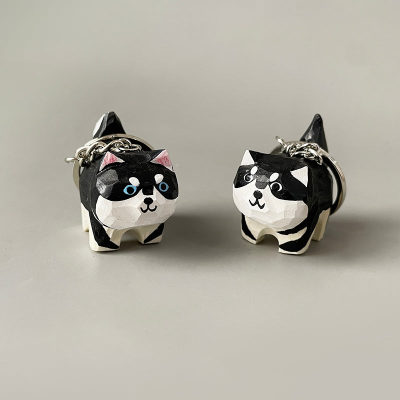 Two hand-carved wooden dog keychains side by side, highlighting the differences in their hand-painted designs
