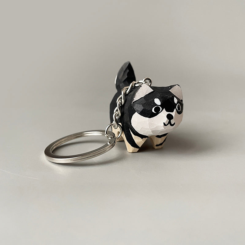Hand-carved wooden husky dog keychain with a close-up view of its side, highlighting the black and white paint and key ring