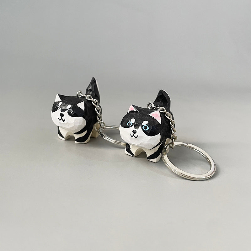 Two hand-carved dog keychains with black and white paint, showing their cute and detailed design