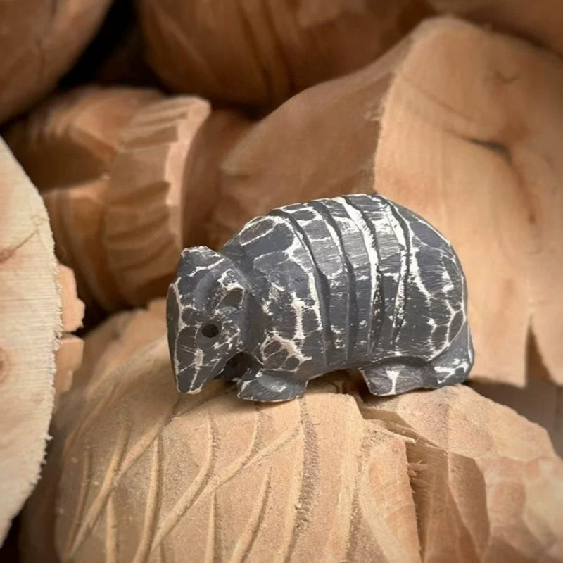 Armadillo wooden figurine resting among carved wood pieces