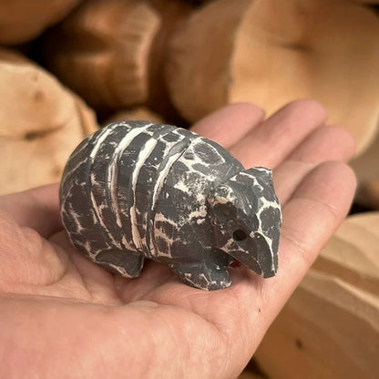 Hand carved armadillo figurine held in palm for scale