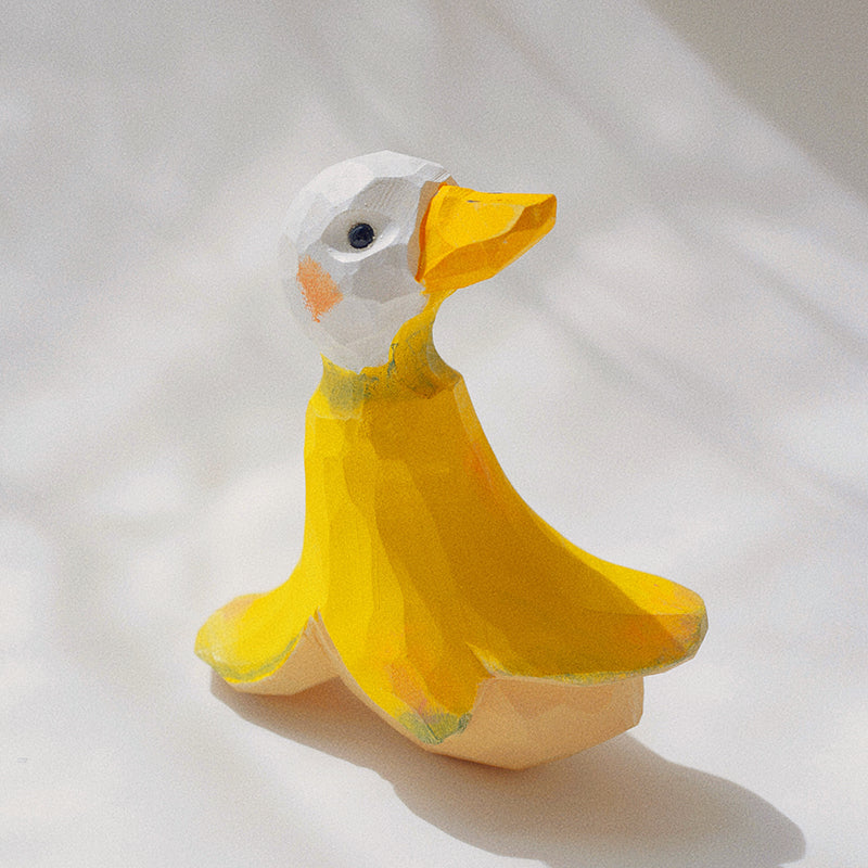 Handmade wooden sculpture of a banana duck on a tabletop.
