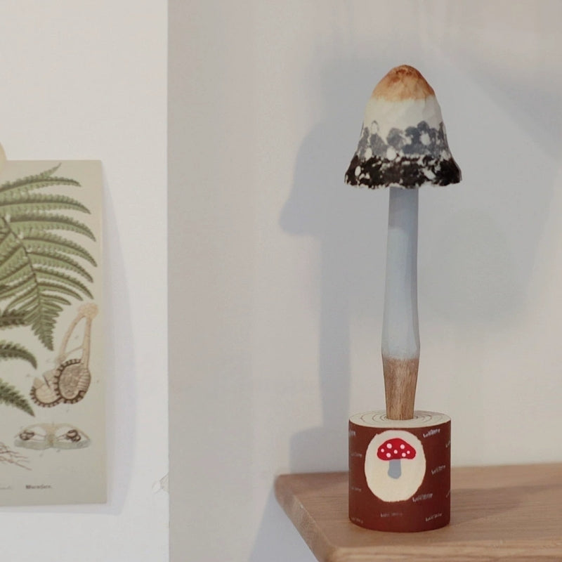 Bell-cap mushroom pen with a cream and dark brown cap in a painted wooden holder.
