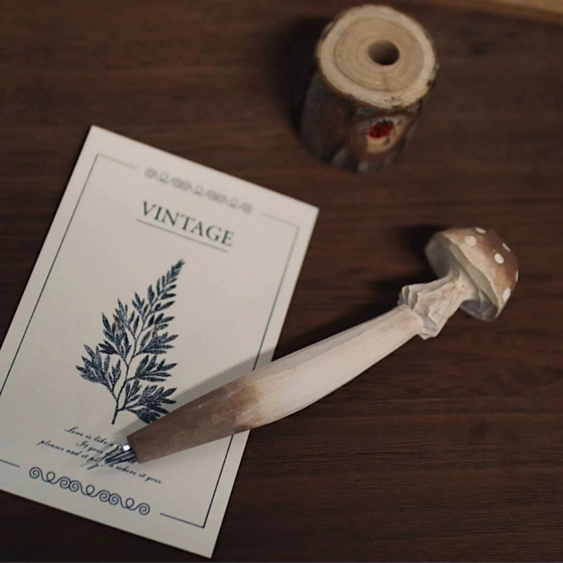 Brown mushroom pen lying beside a wooden holder with its metal writing tip visible.