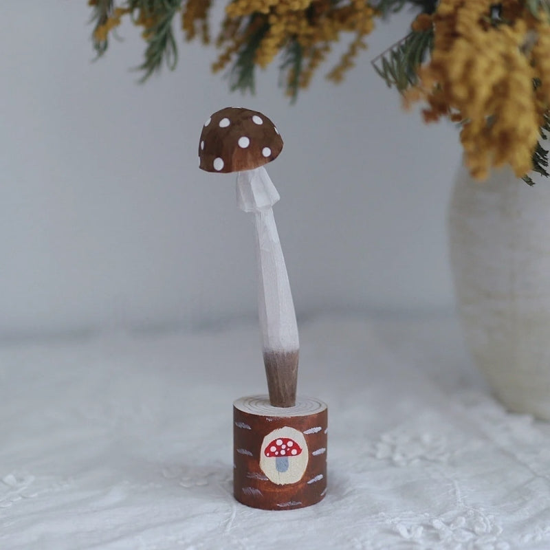 Brown wooden mushroom pen with a white-spotted cap in a holder painted with a red mushroom.