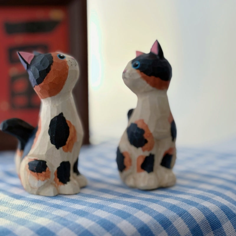 Wooden calico cat figurine viewed from an angled side perspective