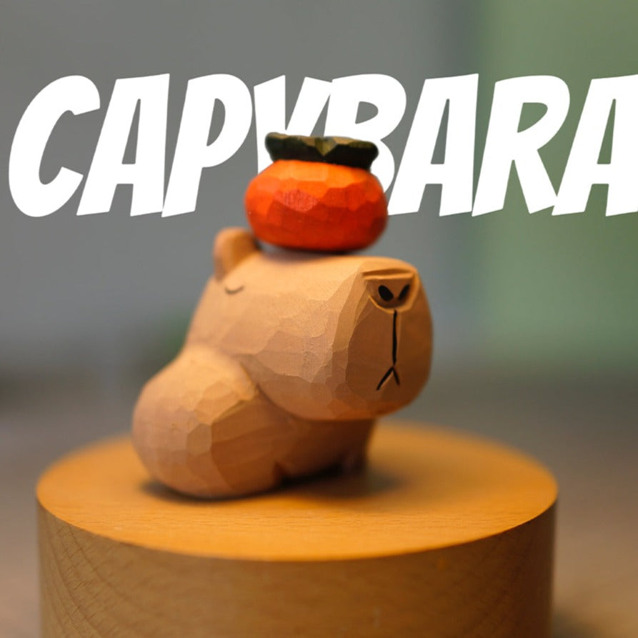 Wooden capybara figurine with a persimmon on its head, displayed on a round wooden stand