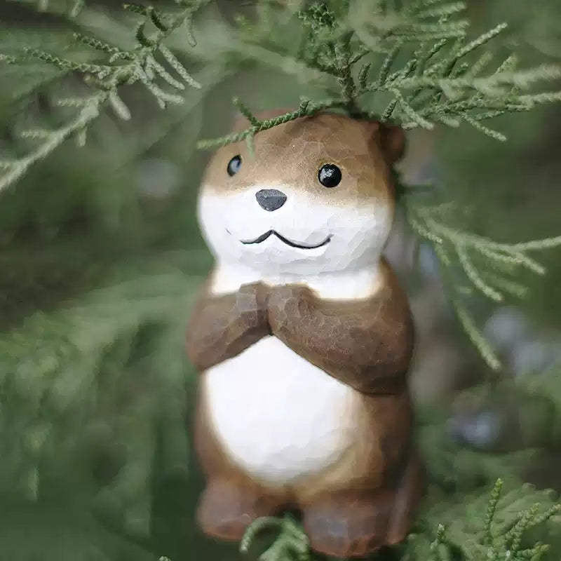 Chibi otter figurine with green cypress foliage backdrop