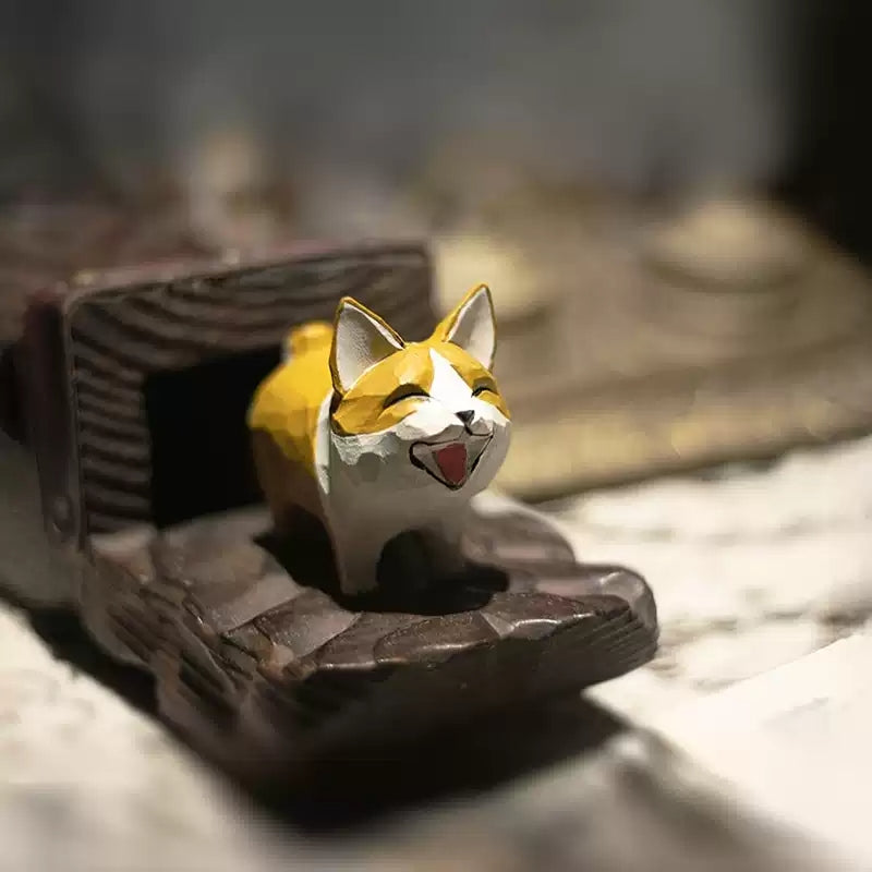 Corgi wood carving with an oversized head and hand-painted smile on a dark wooden display