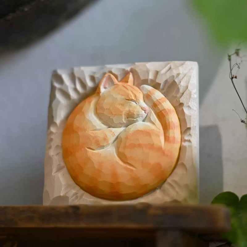 Curled orange tabby cat wood relief on table