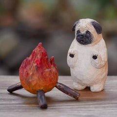 Cute custom dog sculpture of a pug warming by a fire, carved and painted with personality and charm.
