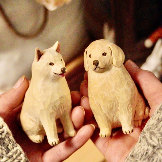 Pair of hand-carved custom dog sculptures resting in hands, capturing your pup’s true character in wood.