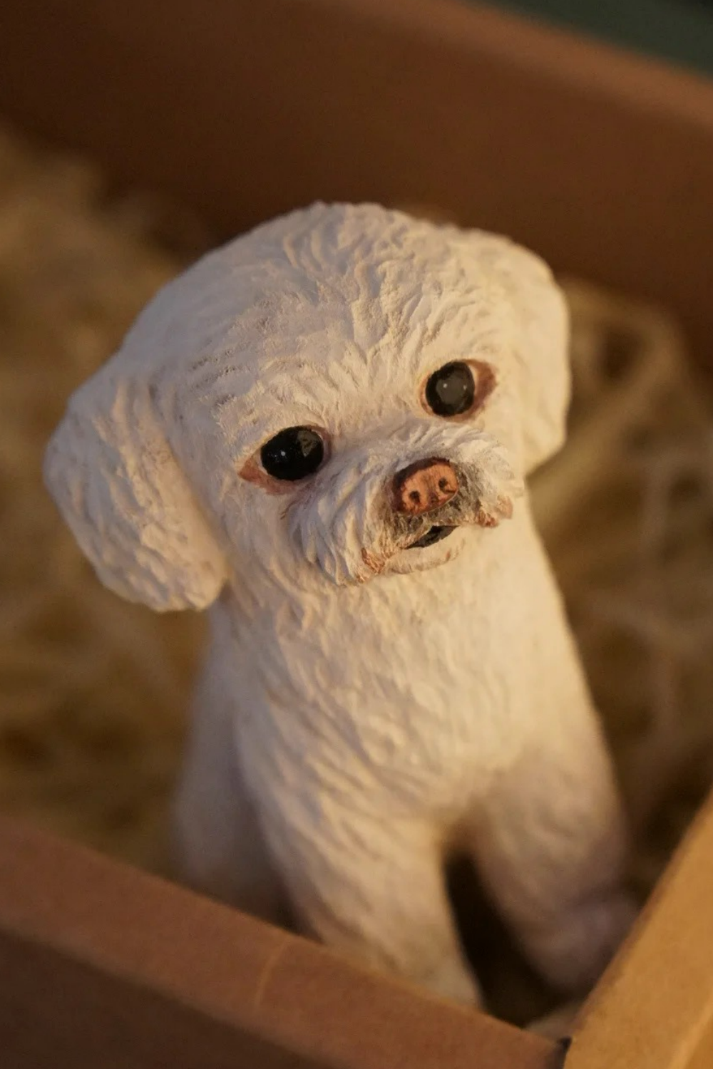 Hand-carved white Maltese figurine with a pink nose and a slightly tilted head.