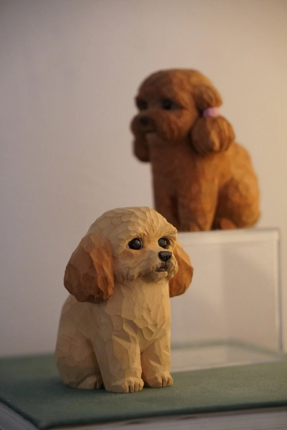 Two hand-carved wooden dog figurines with floppy ears, one cream-colored and one brown.