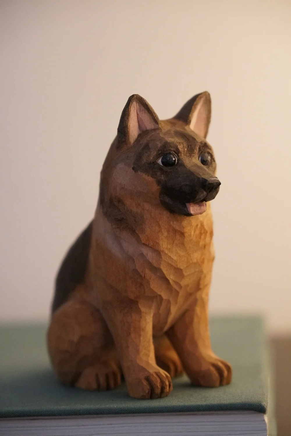 Hand-carved wooden German Shepherd figurine sitting upright with pointed ears and black-and-tan markings.