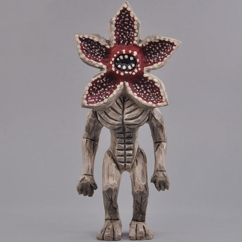Front view of hand-carved wooden Demogorgon figure from Stranger Things on gray background.