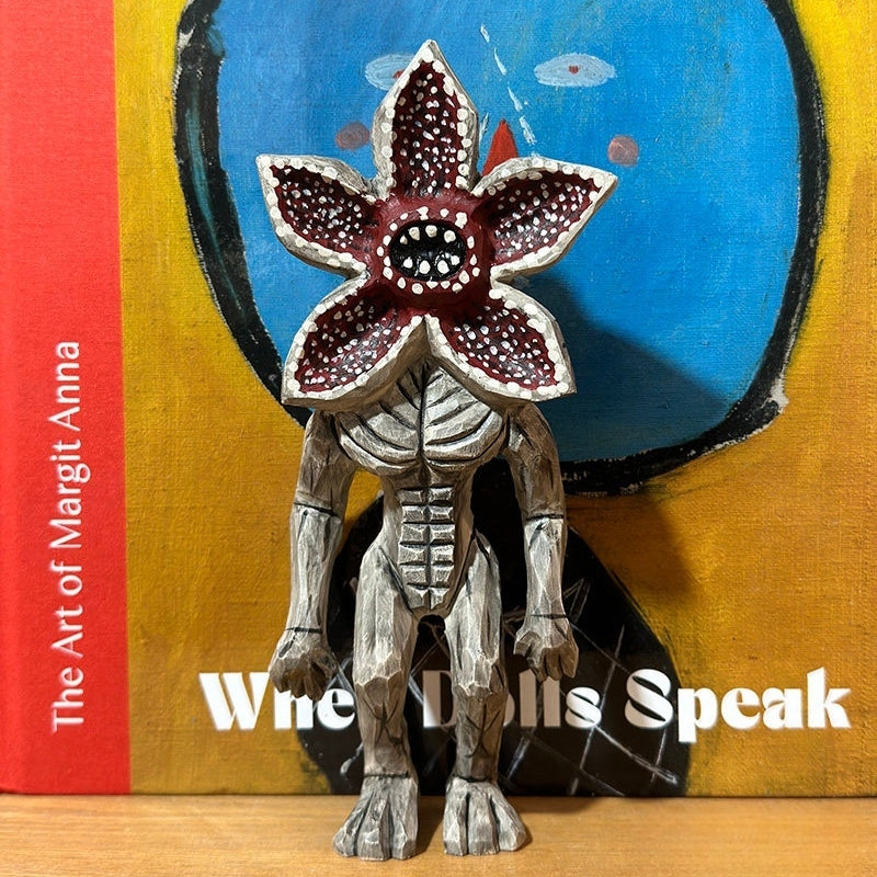 Demogorgon figure posed in front of colorful modern artwork, adding contrast to the rustic wood.
