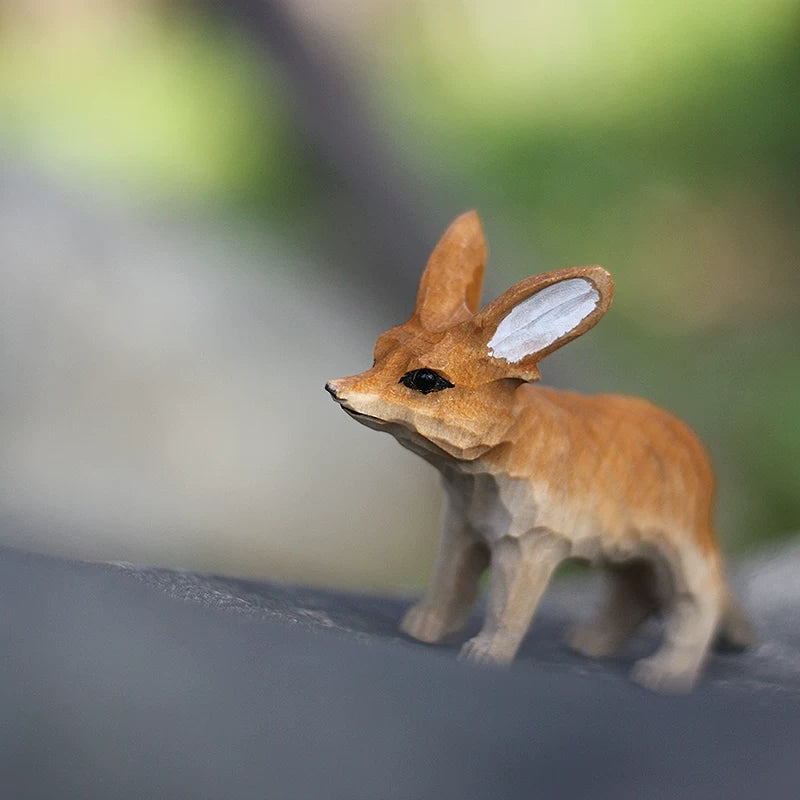 Hand-carved fennec fox figurine side view on dark surface